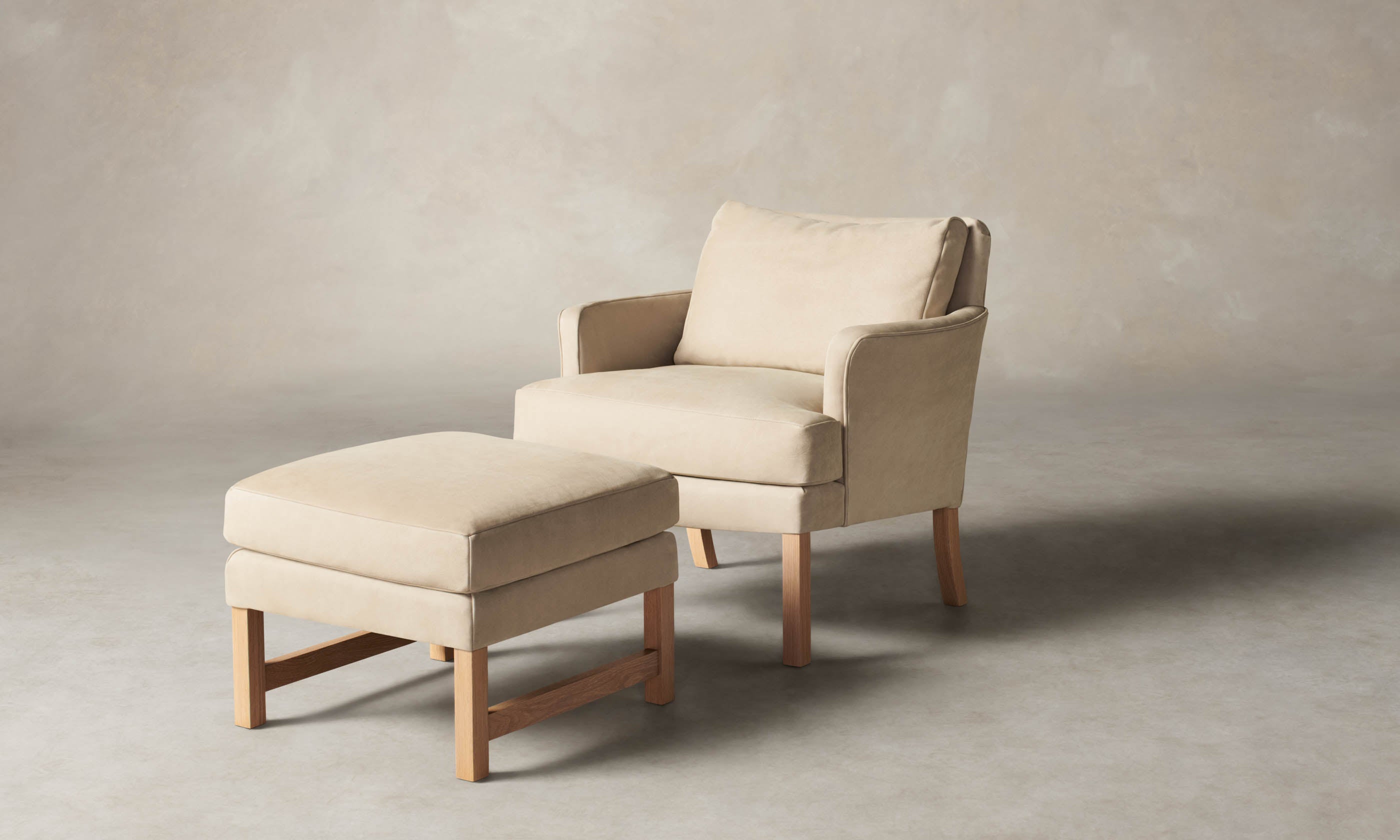 kaye leather accent chair in grey nubuck leather with wooden legs and a leather ottoman set