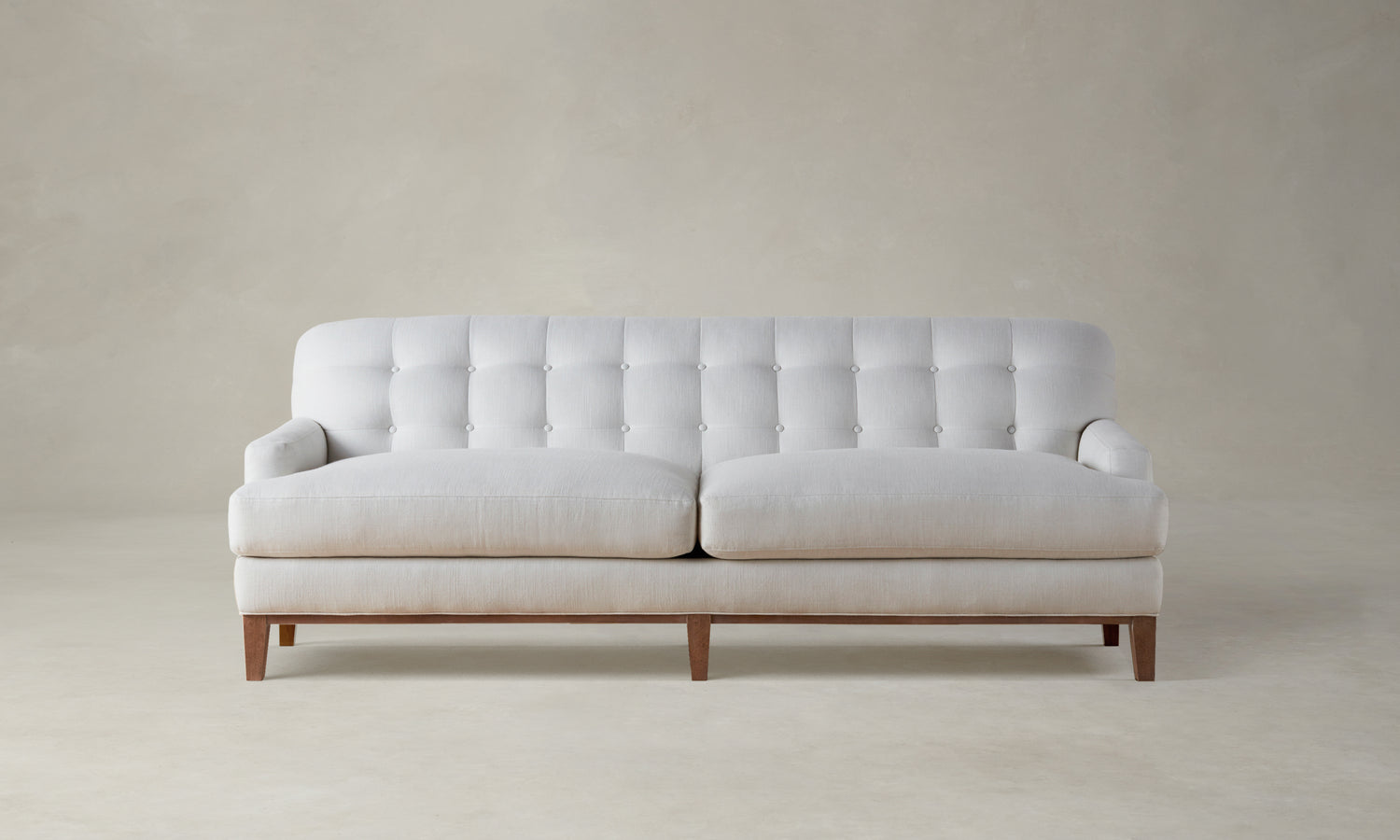 ludlow tufted sofa in white linen with wooden base and legs