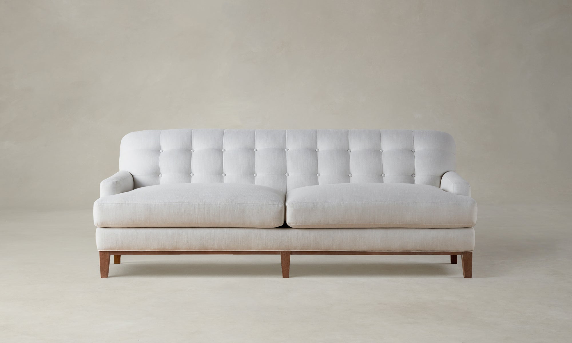 ludlow tufted sofa in white linen with wooden base and legs